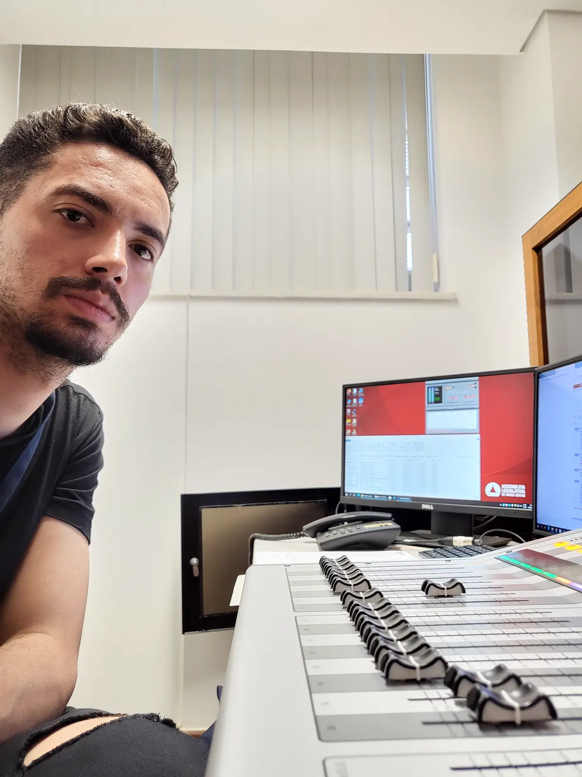 Matheus Borges numa cabine de som com mesa digital e monitores de computador.