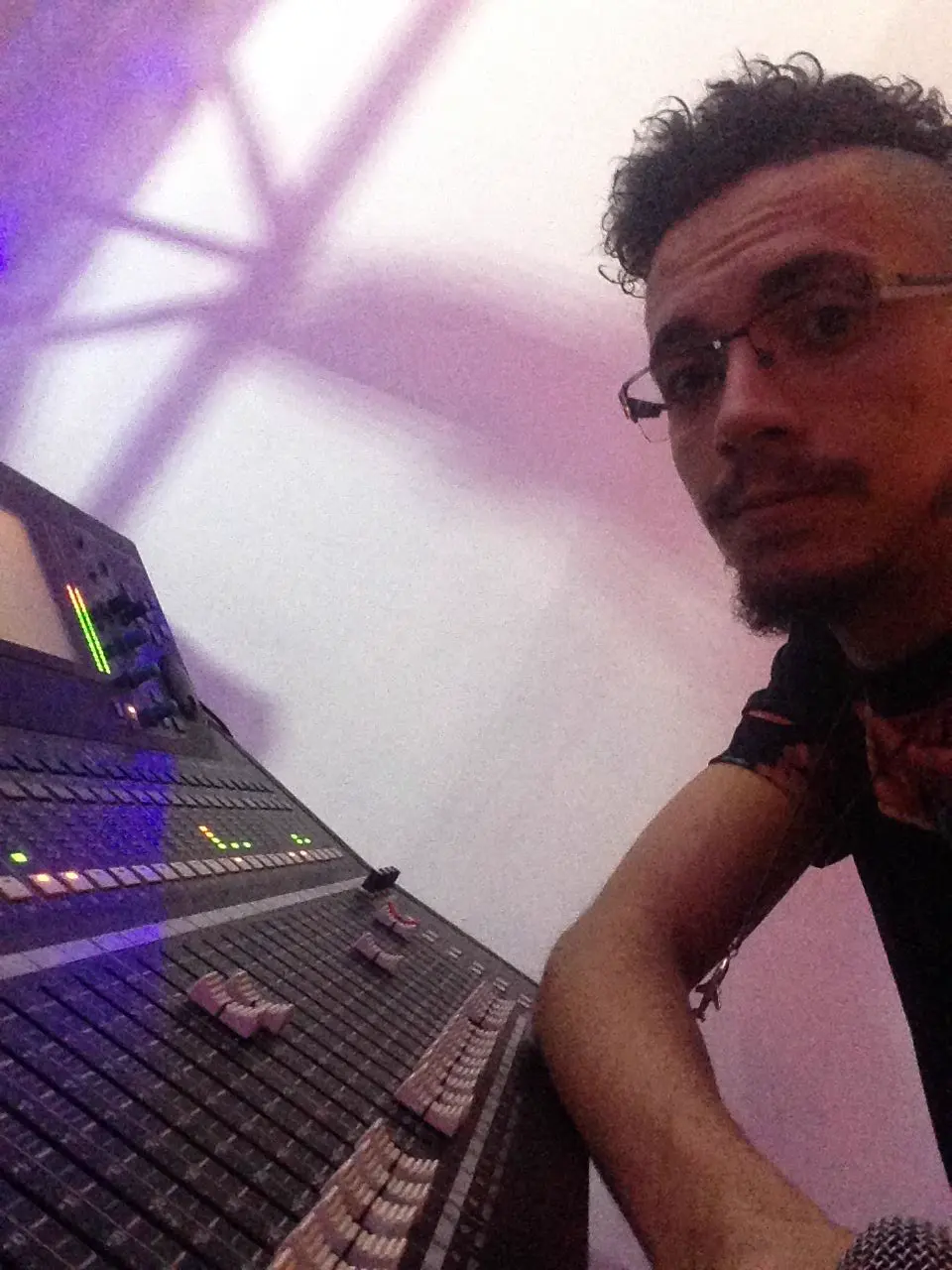 Matheus Borges na mesa de som, sob a luz do palco.