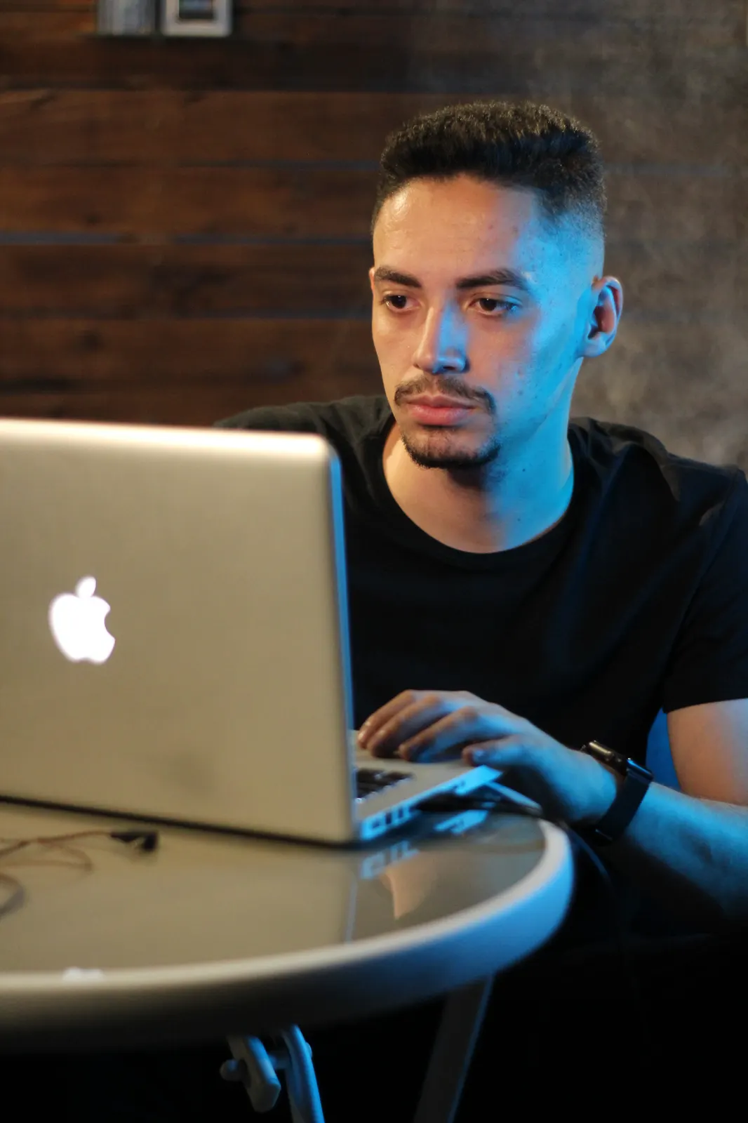 Matheus Borges trabalhando no notebook, sob luz azul.