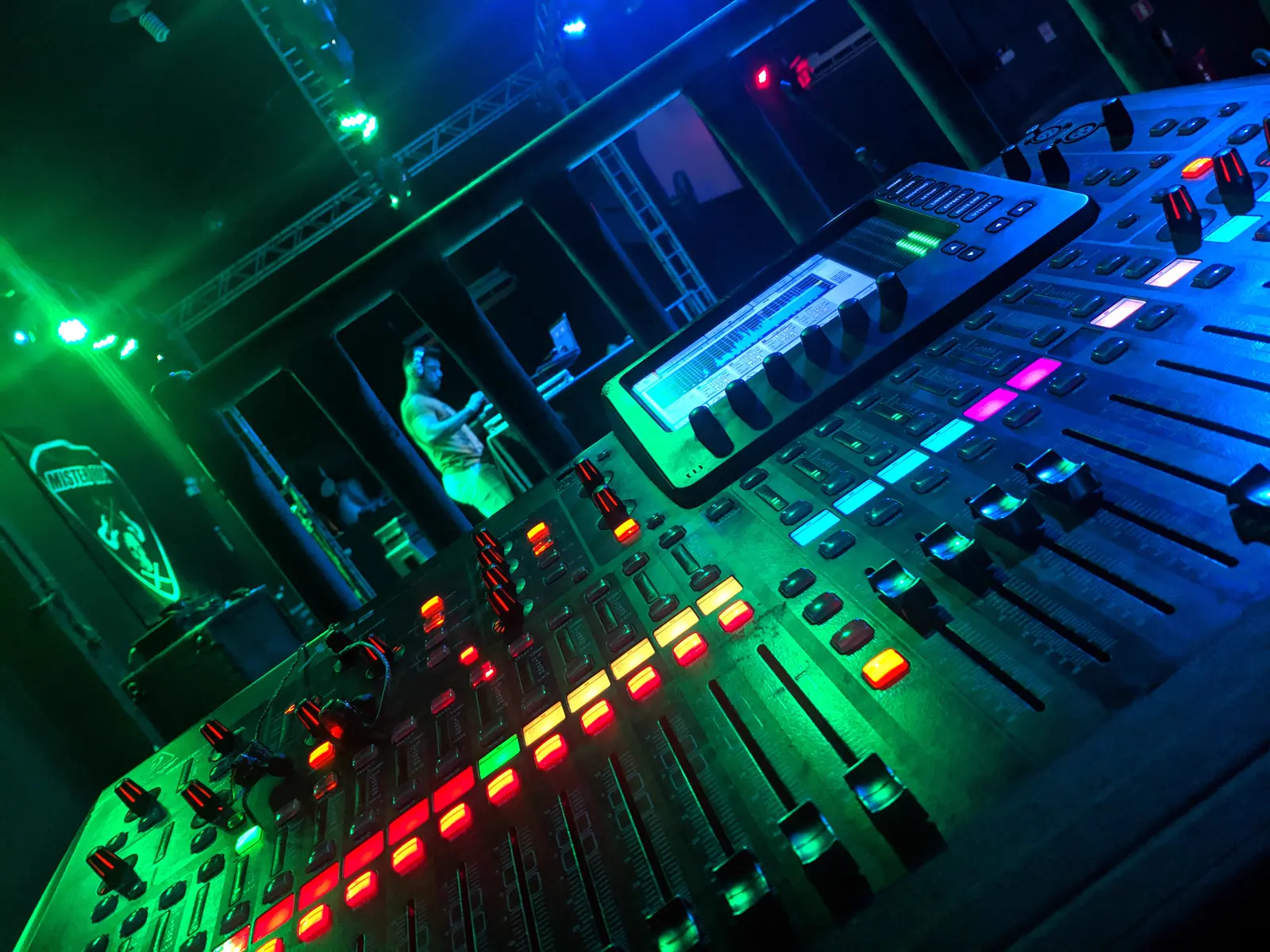 Mesa de som digital iluminada pelas luzes do palco durante um show.